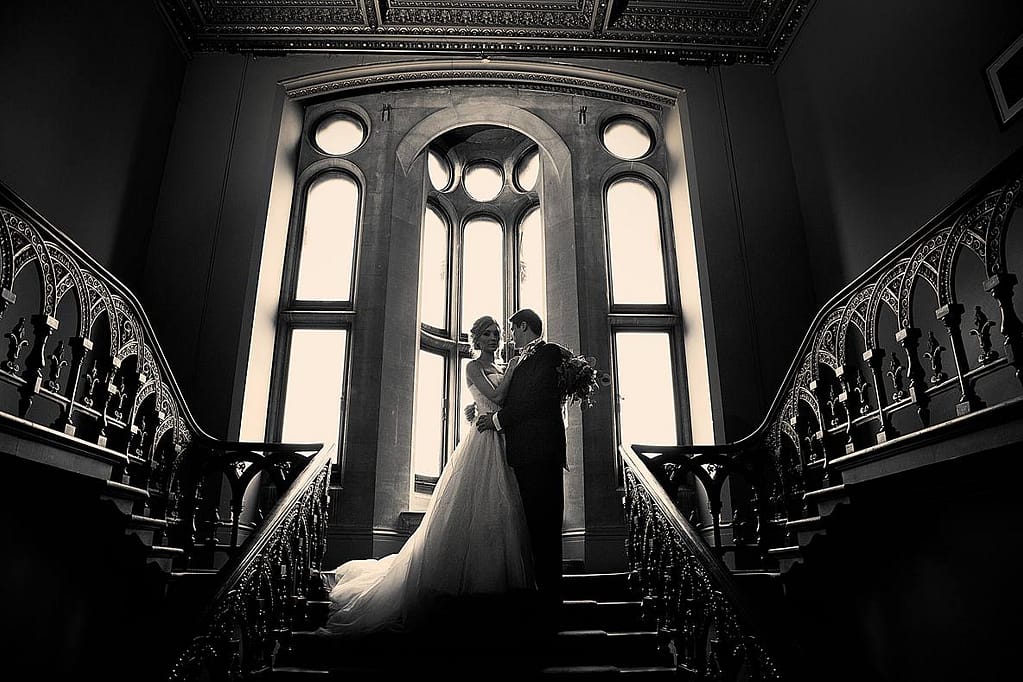 couple standing at the top of the gran Grittleton house staircase for wedding photographer