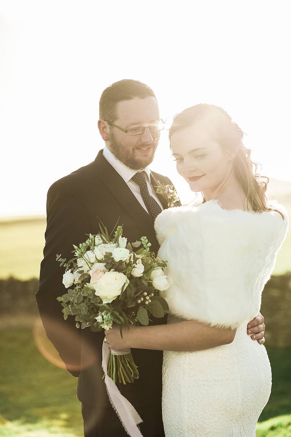 bride and groom with sunlight coming through Kingscote Barn wedding