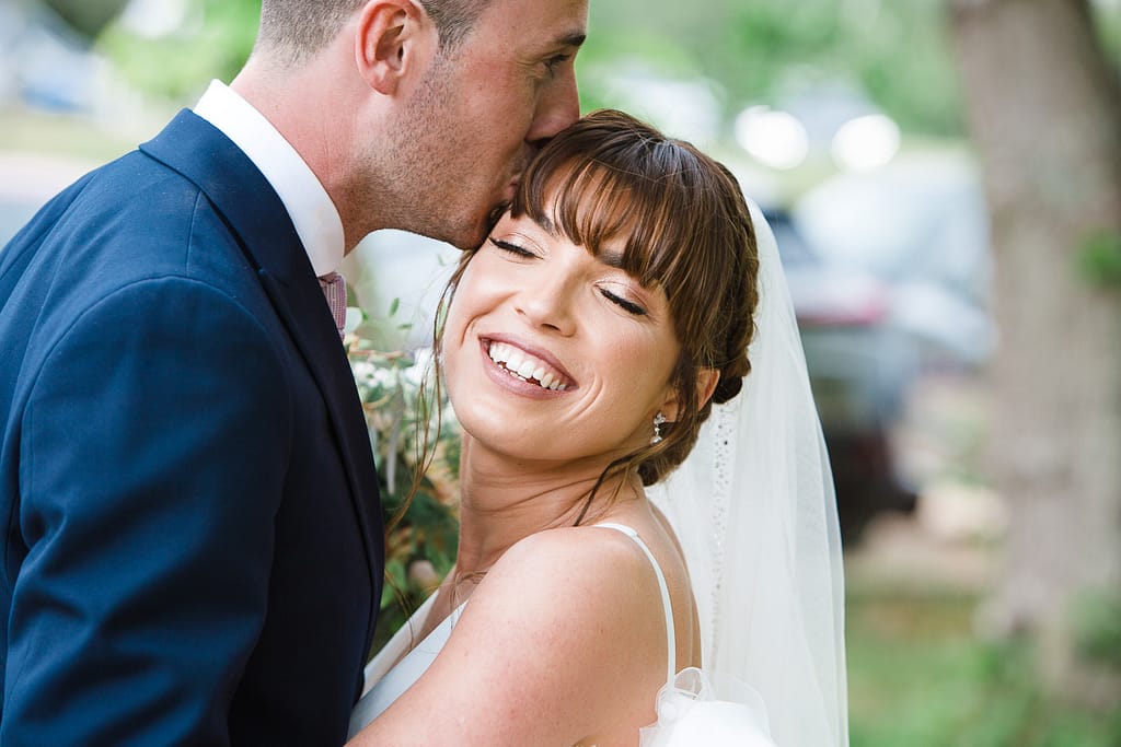groom kissing bride at Frogmill Inn cotswold wedding venue