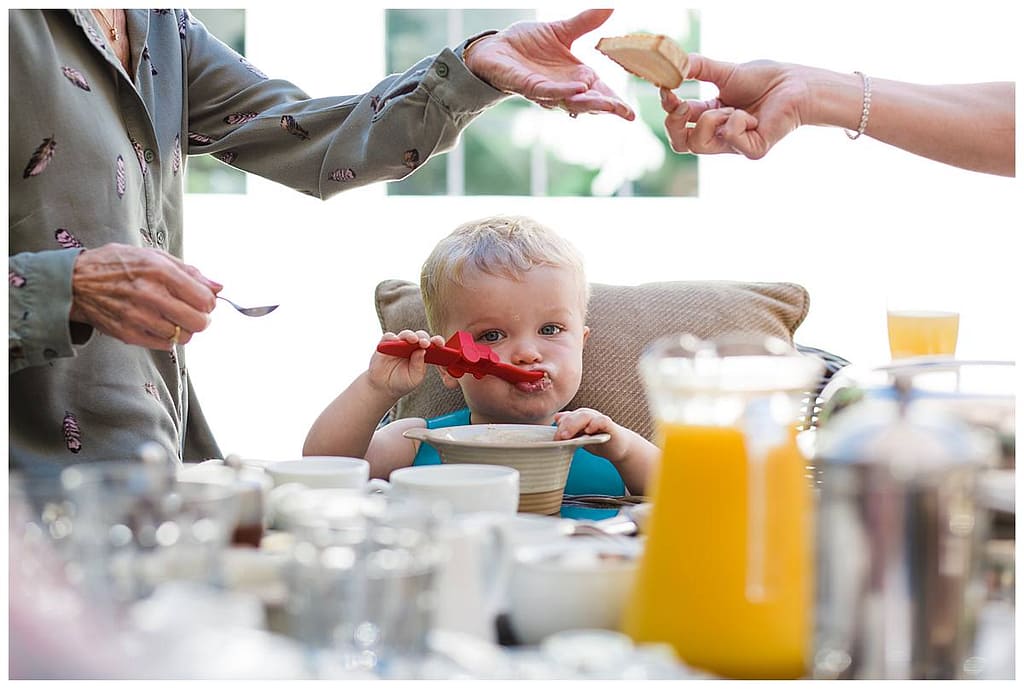 little boy eating breakfast with red spoon wedding day Barnsley house wedding photography