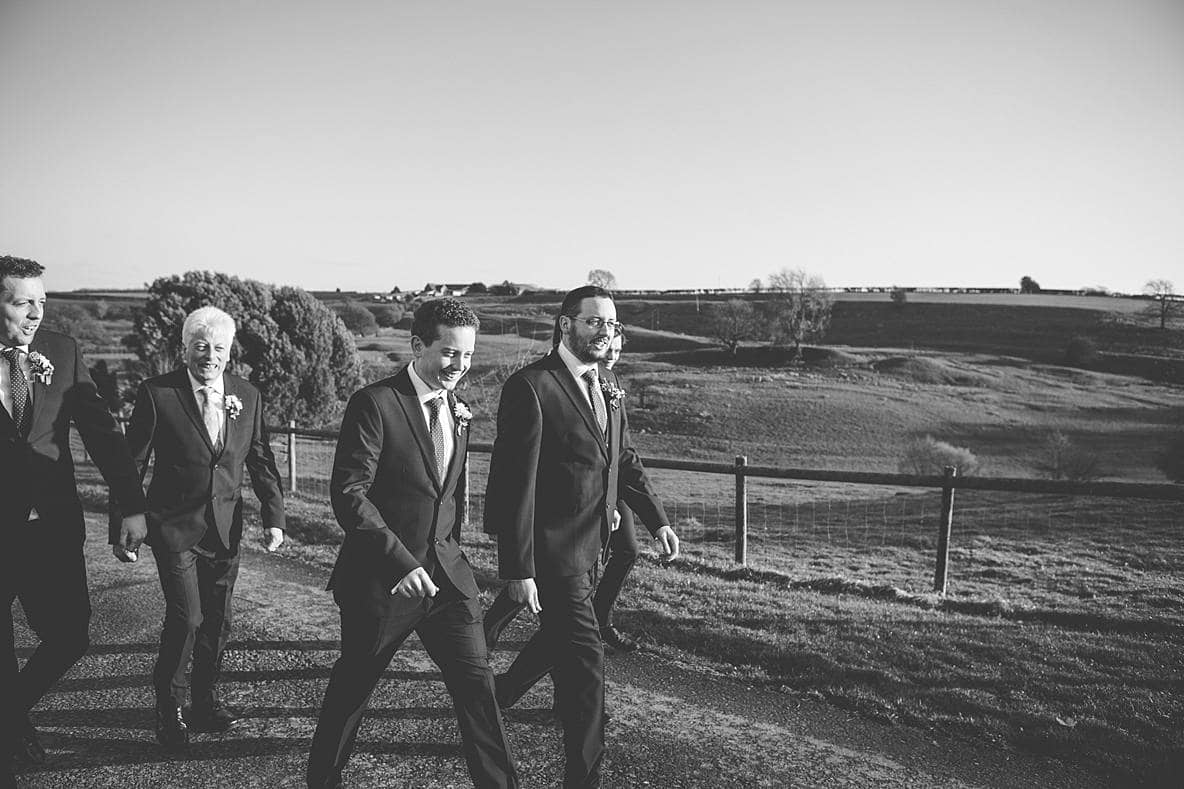 groomsmen walking near fields Kingscote Barn wedding winter