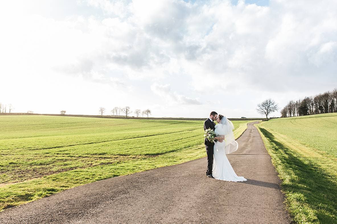 couple kissing in field Kingscote Barn January wedding photographer