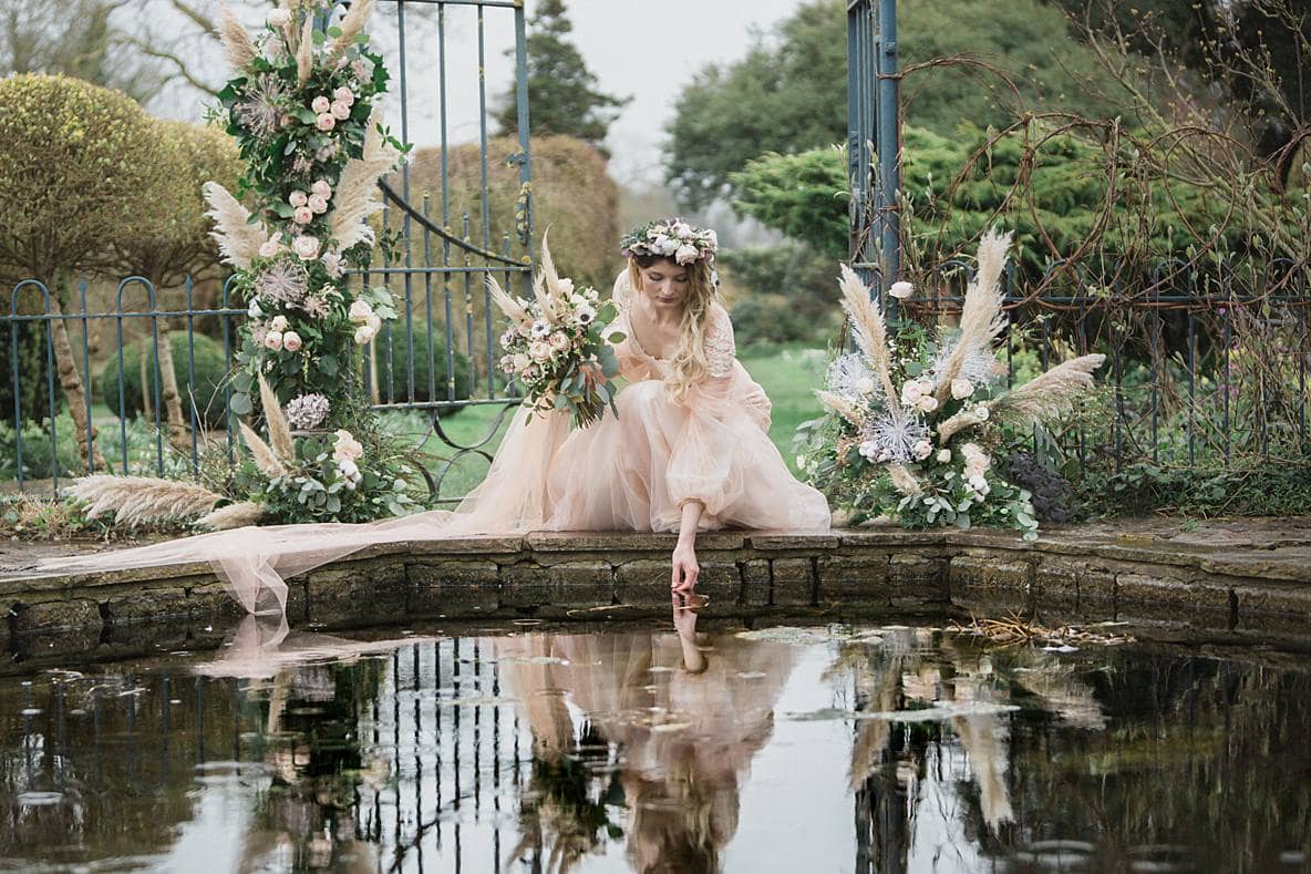 Barnsley House bride touching water for wedding photographer 