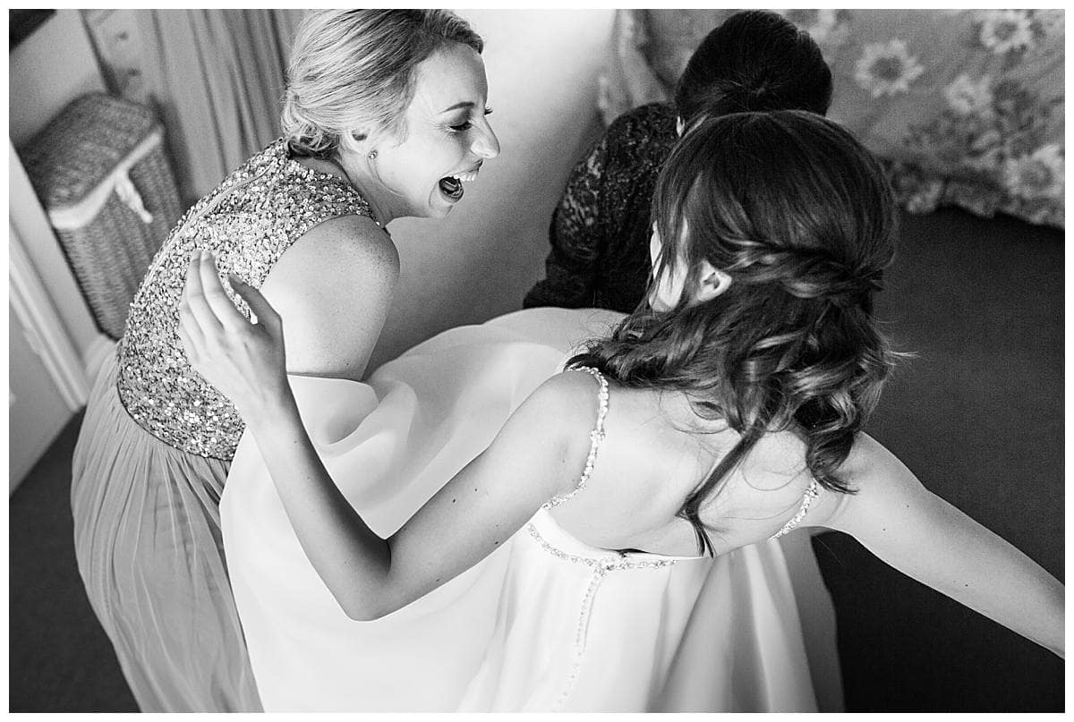bridesmaid helping bride get ready for her wedding day
