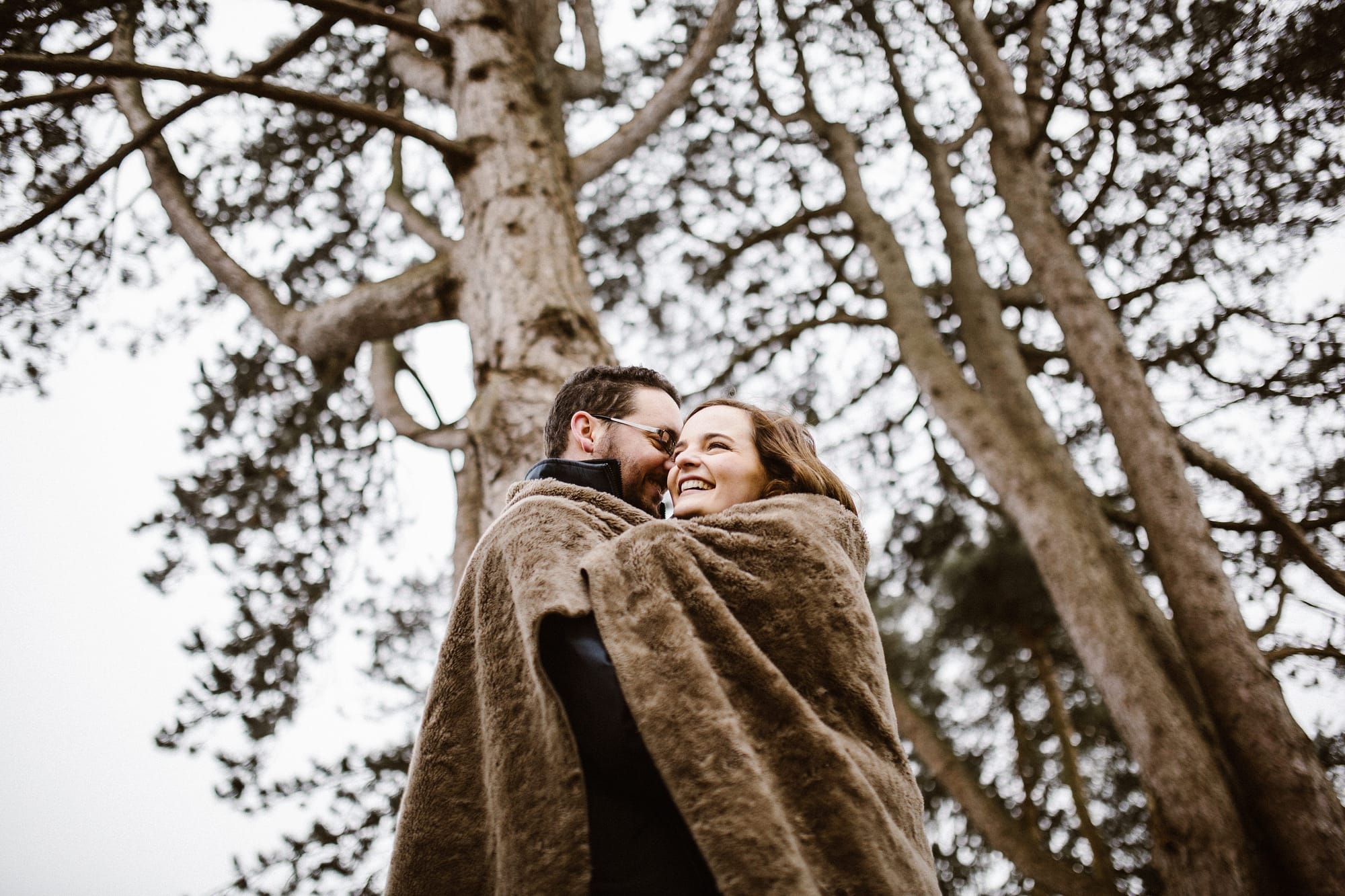 cuddling couple on cold day at pre wedding shoot Kingscote Barn photography 