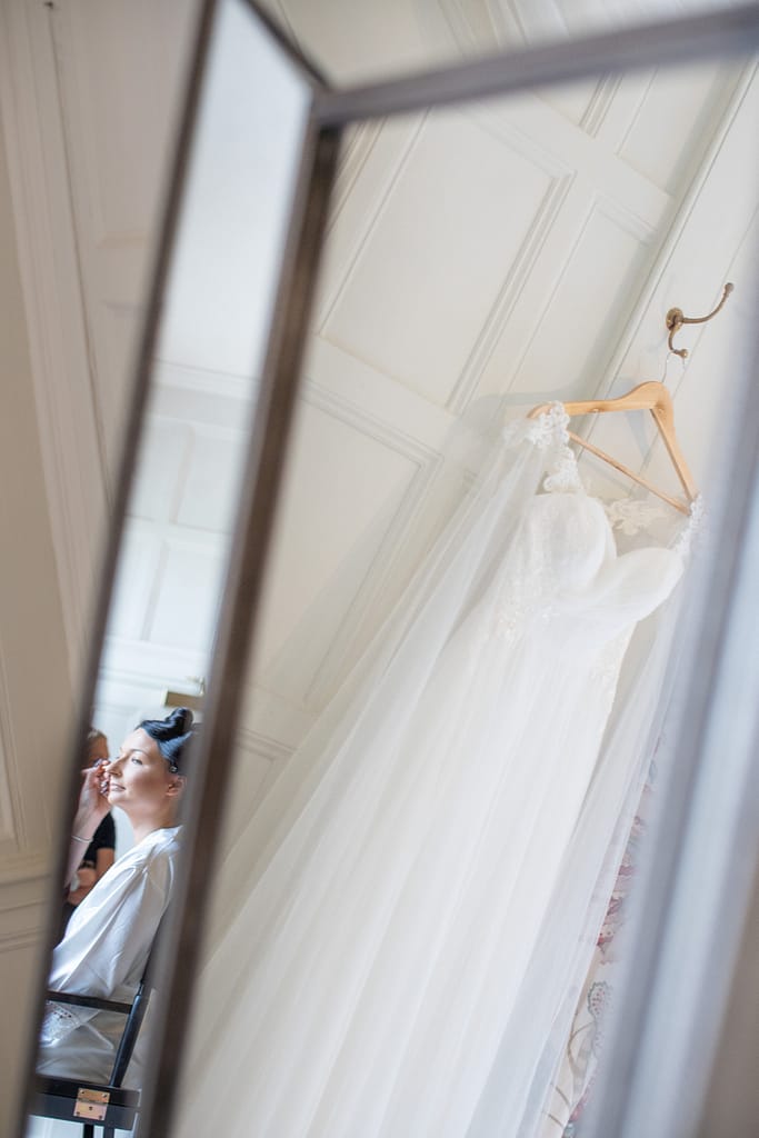 bride having make up done with wedding dress hanging Elmore court