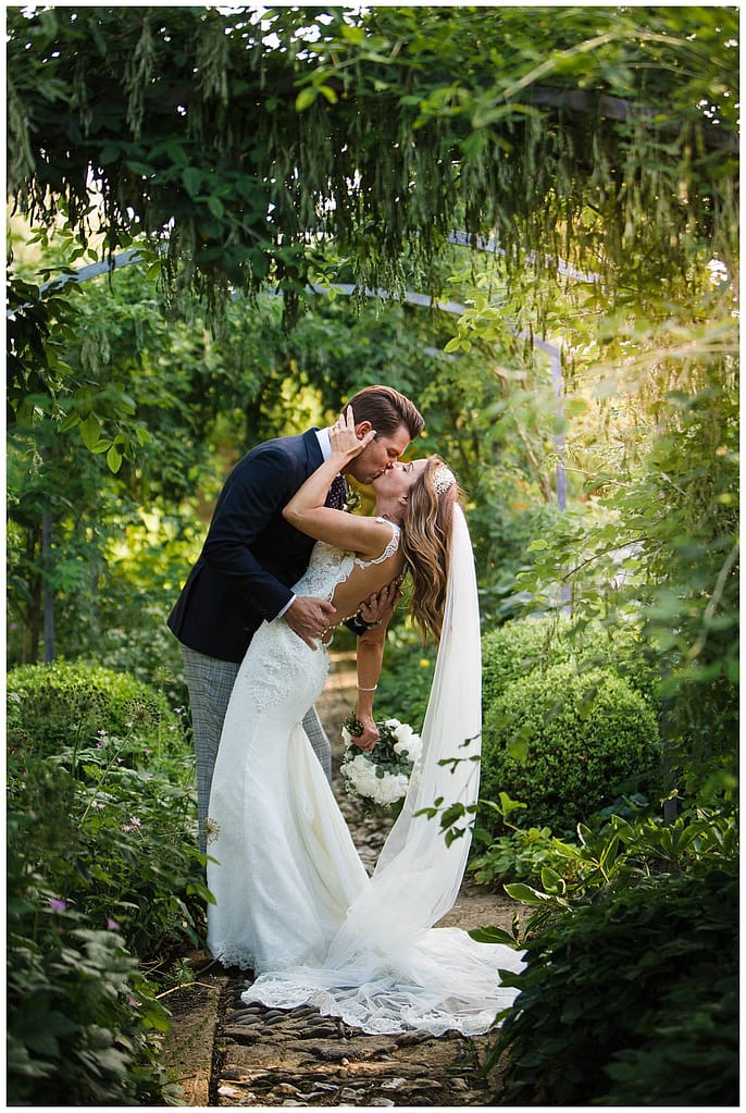 couple kissing in Barnsley House gardens for wedding photographer