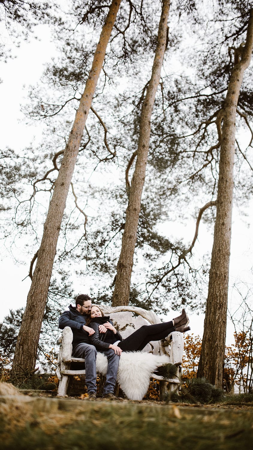 couple sitting on bench amongst trees Kingscote Barn wedding photographers